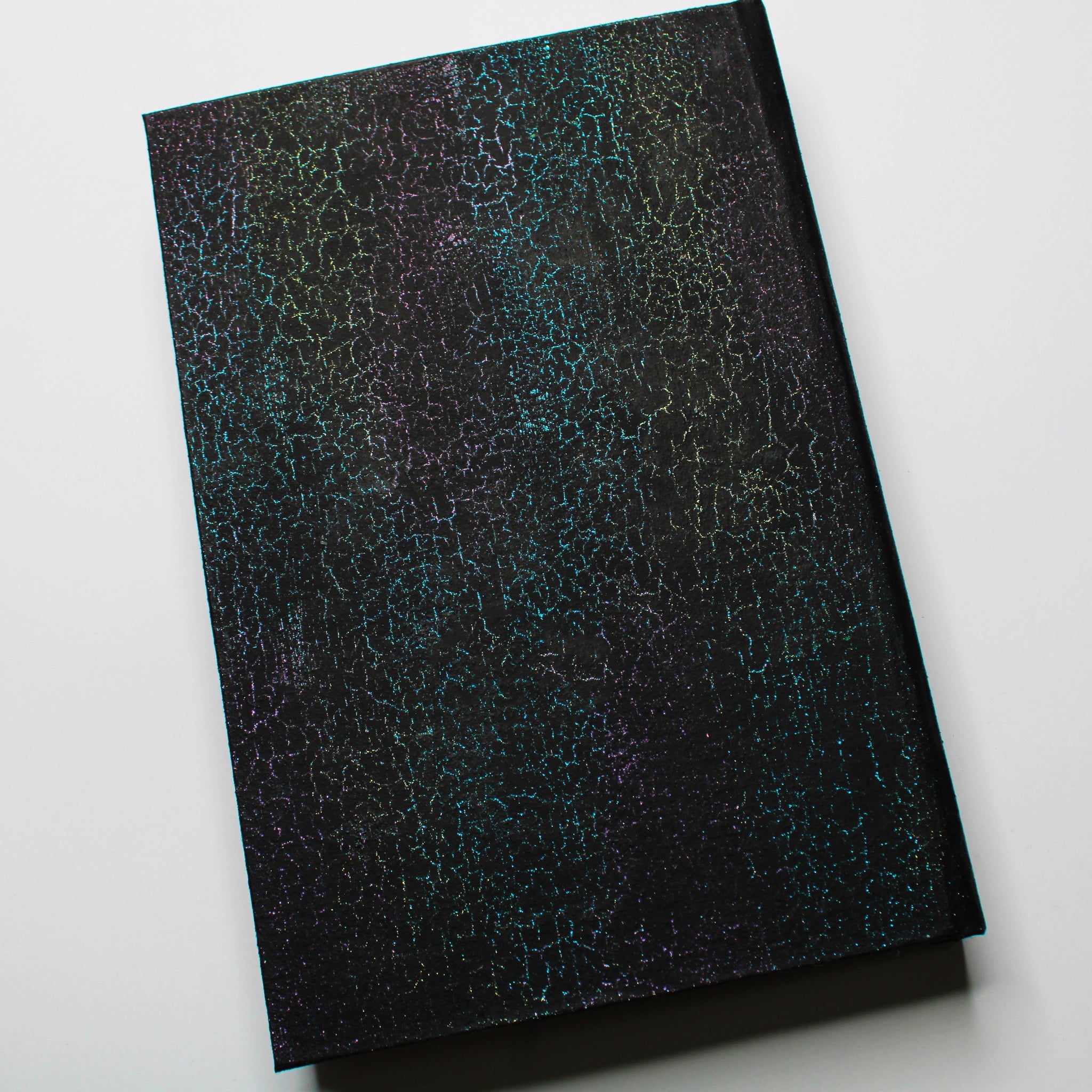 The back of a black journal with a colorful, crackled pattern.