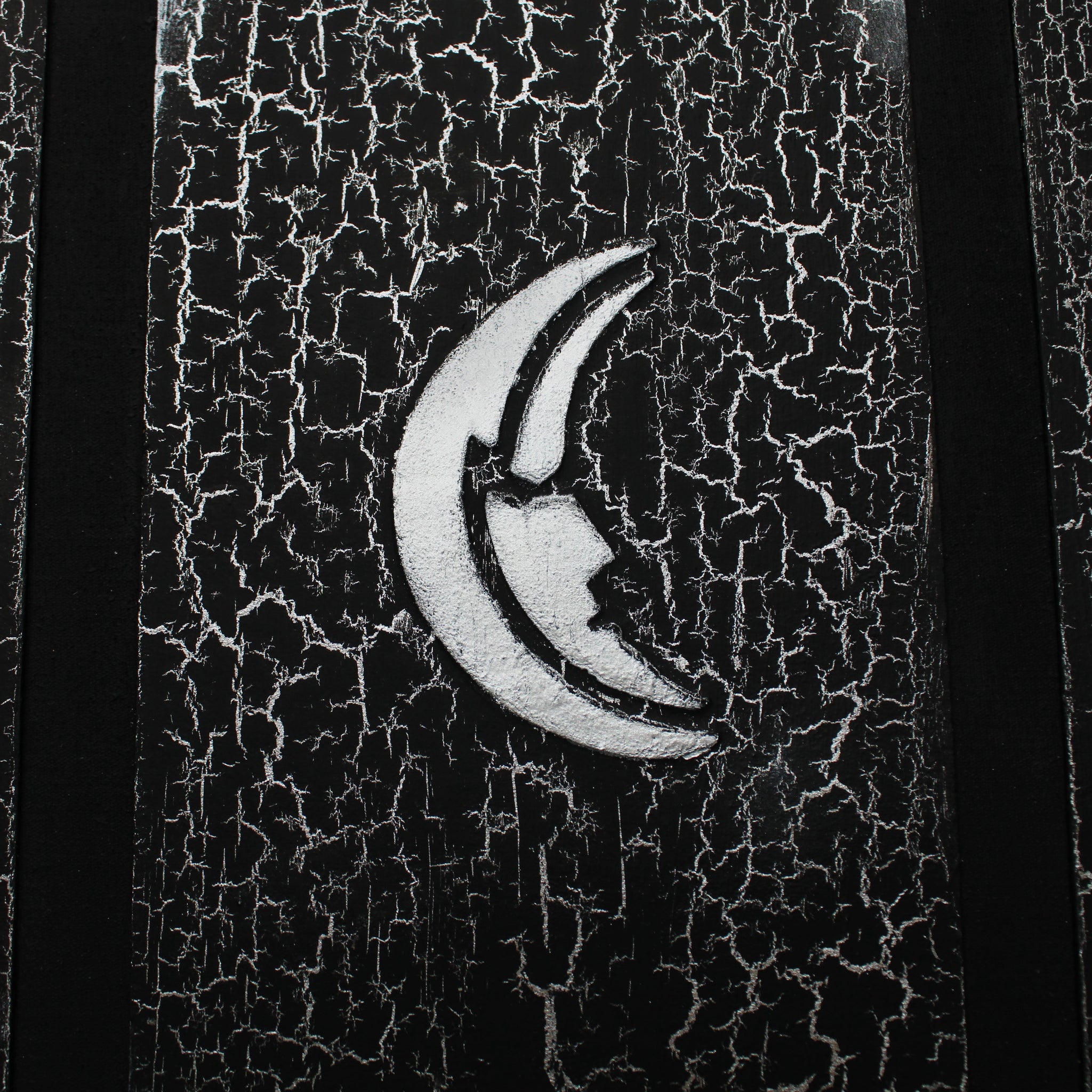 A black journal with a silver, crackled pattern on the cover. The cover has a 1/2 inch border, and a black 1/2 inch recessed area that surrounds a rectangular flat central panel with an embossed silver moon in the center which is the main focus of the image.